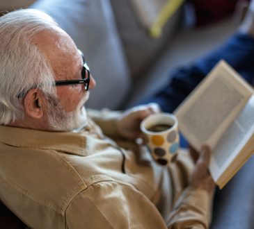 Man reading book on couch with coffee