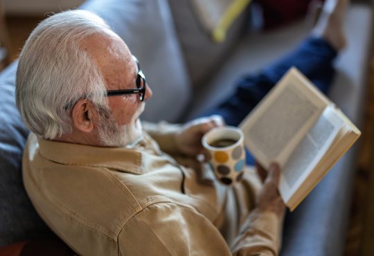 Man reading book on couch with coffee