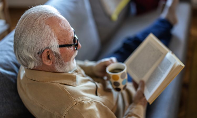 Man reading book on couch with coffee