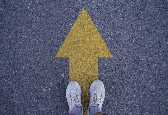 Person standing on arrow on road