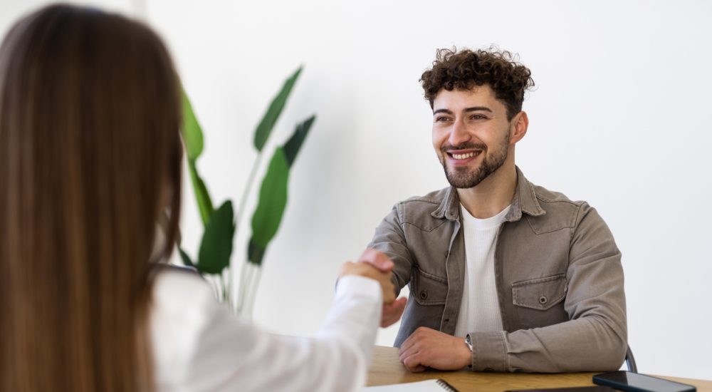 Two people shaking hands over desk