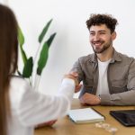 Two people shaking hands over desk