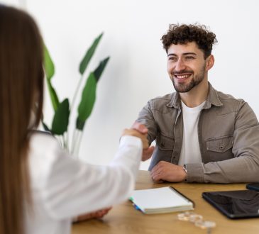 Two people shaking hands over desk