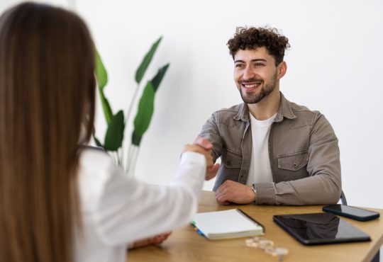 Two people shaking hands over desk