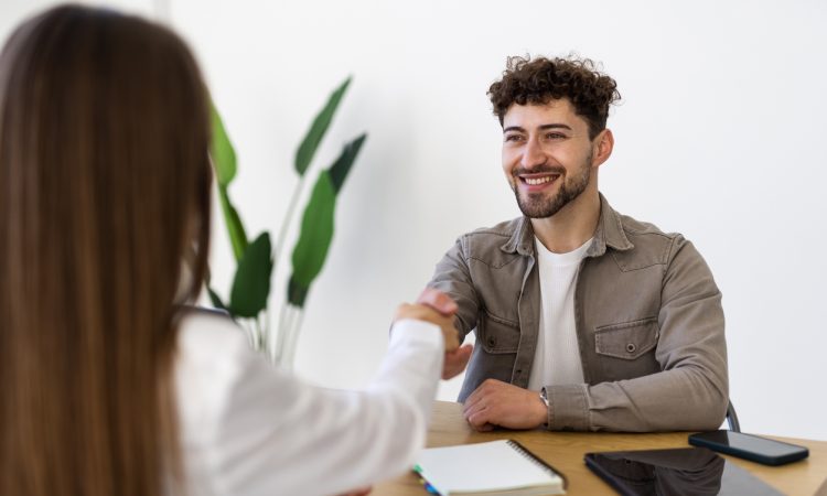 Two people shaking hands over desk