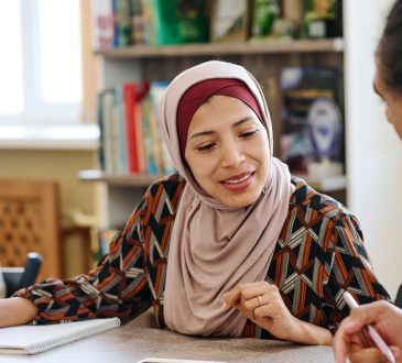 Muslim woman wearing hijab sitting at table in library