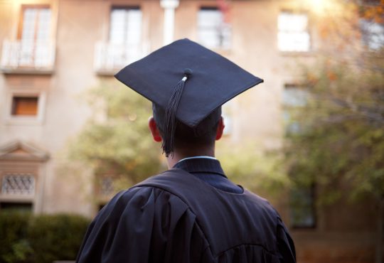 Student wearing graduation cap pictured from behind