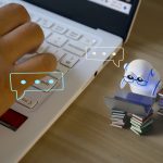 Photo illustration with tiny robot working on tiny computer alongside closeup of human hand on keyboard