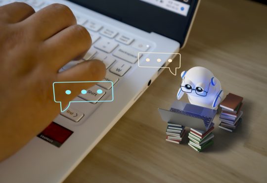 Photo illustration with tiny robot working on tiny computer alongside closeup of human hand on keyboard