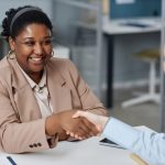 Two people shaking hands in office