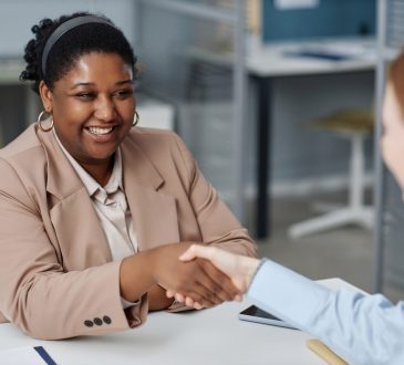 Two people shaking hands in office