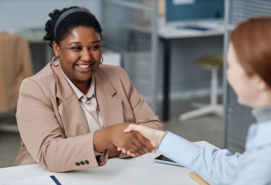 Two people shaking hands in office