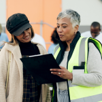 Person wearing safety vest talking to volunteer at food sort