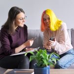 Teen girl with colourful hair talking to adult on couch