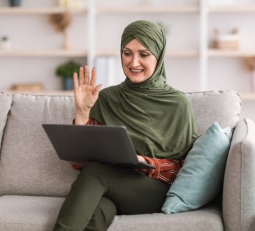 Woman joining video call on laptop on couch