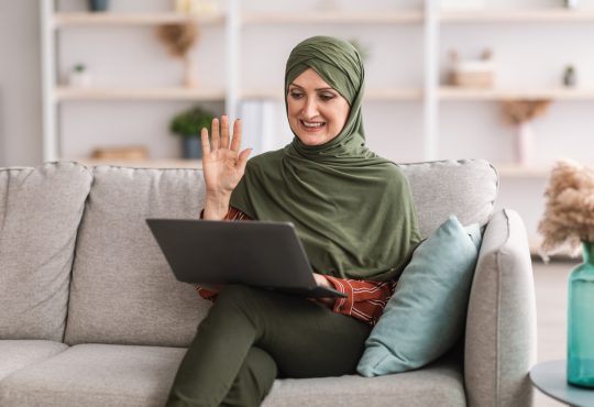 Woman joining video call on laptop on couch