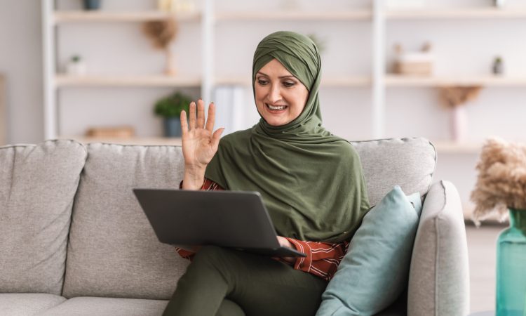 Woman joining video call on laptop on couch