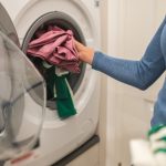 Woman putting clothes in washing machine