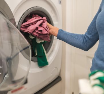 Woman putting clothes in washing machine