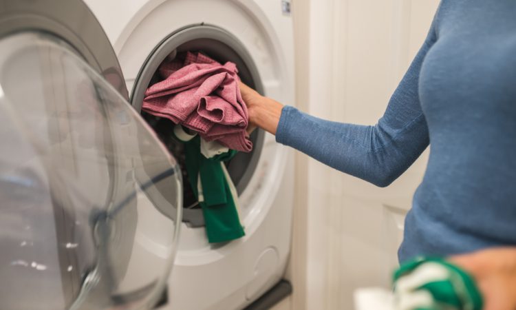 Woman putting clothes in washing machine