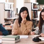 Group of students talking at table in library