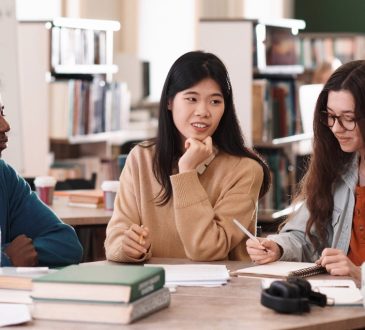 Group of students talking at table in library