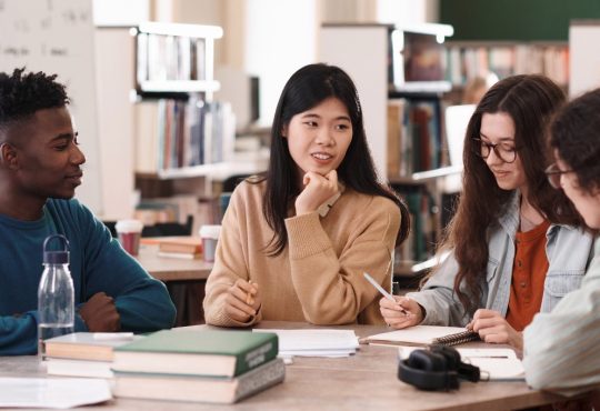 Group of students talking at table in library