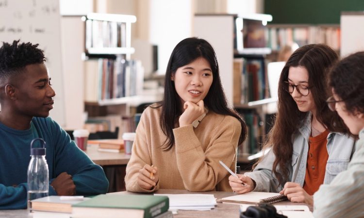 Group of students talking at table in library