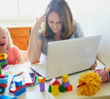 Stressed mom trying to work on computer at home beside screaming child