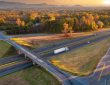 Freeway overpass junction with fast moving traffic cars and trucks in American rural area at sunset.