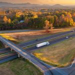 Freeway overpass junction with fast moving traffic cars and trucks in American rural area at sunset.