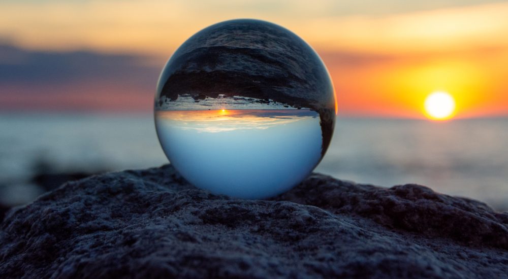 Glass ball on a rock at sunset on the beach