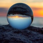 Glass ball on a rock at sunset on the beach