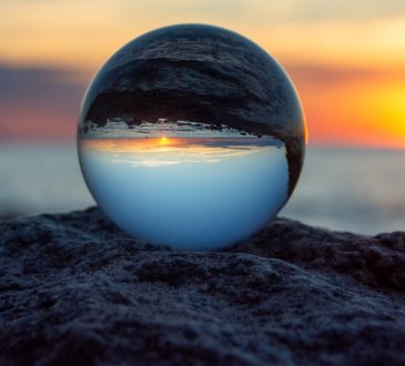 Glass ball on a rock at sunset on the beach