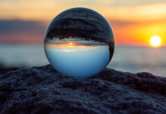 Glass ball on a rock at sunset on the beach