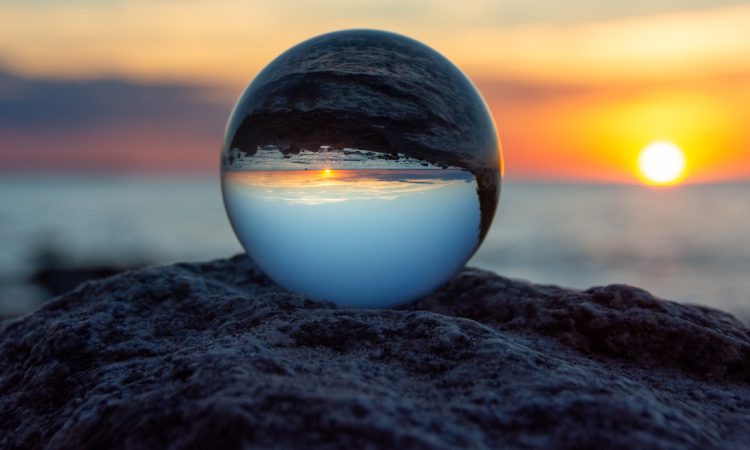 Glass ball on a rock at sunset on the beach