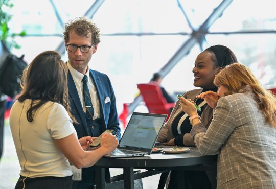 People gather around a high-top table at a conference