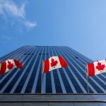 Three Canadian flags flying in front of business building in Ottawa