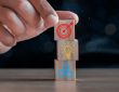 Closeup of hand stacking wooden blocks with icons of bullseye, lightbulb and gears