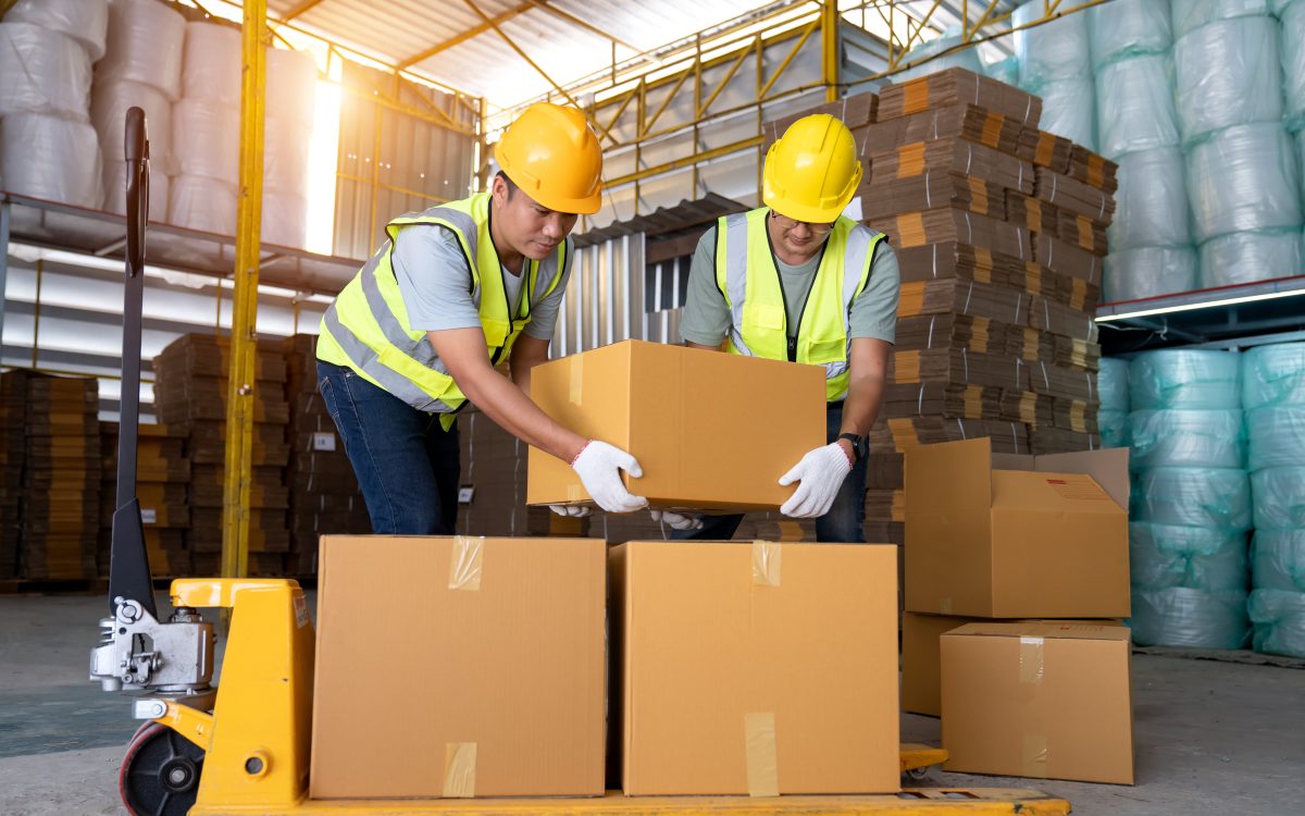 Warehouse workers work in teams and lift sealed cardboard boxes
