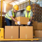 Warehouse workers work in teams and lift sealed cardboard boxes