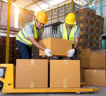 Warehouse workers work in teams and lift sealed cardboard boxes