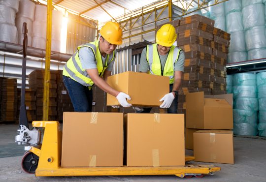 Warehouse workers work in teams and lift sealed cardboard boxes