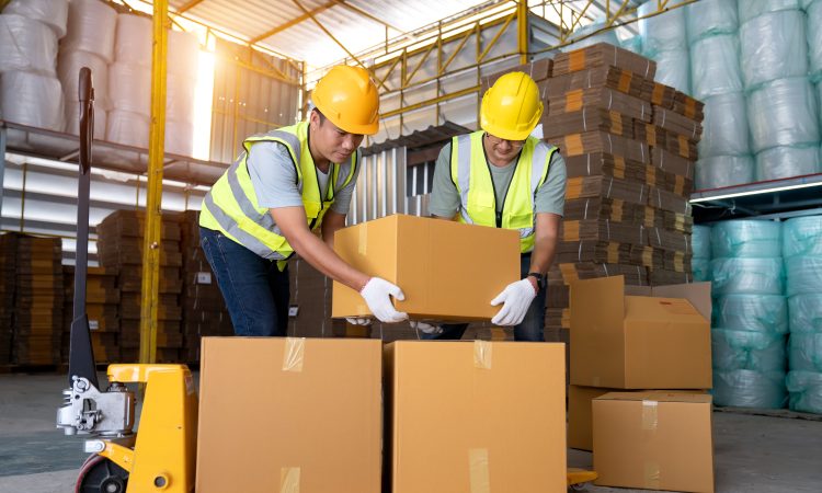 Warehouse workers work in teams and lift sealed cardboard boxes