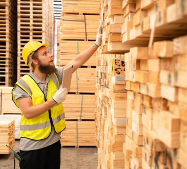 worker checking stock of wooden pallets in storage warehouse