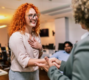 Two people shaking hands in office