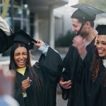 Group of graduates in caps and gowns celebrating outside