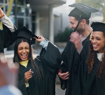 Group of graduates in caps and gowns celebrating outside