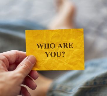 Man holding yellow paper note with question Who are you