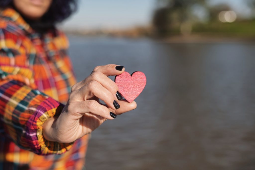 Person holding red wooden heart in hand
